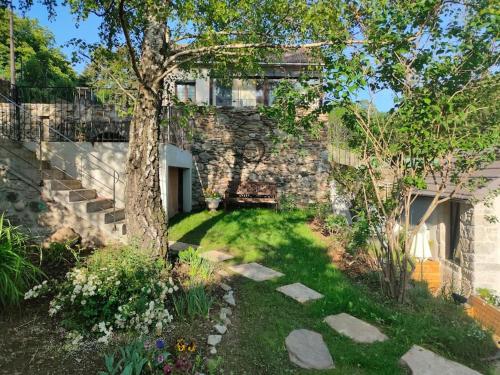 维莱福尔Le Secret du Moulin, agréable tiny house Villefort的一座花园,花园内种有树木,一座石头建筑