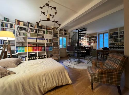 吉维尼L'Atelier du Paysagiste - maison d'artiste的一间卧室配有床、椅子和书架