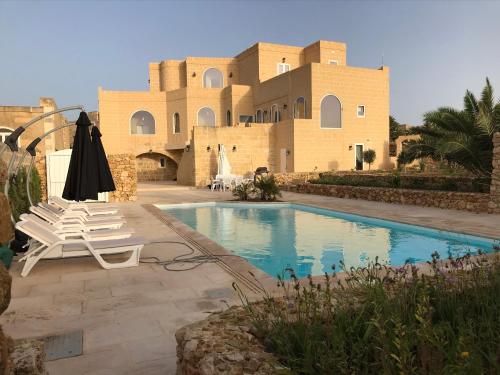 阿尔卜Newly Converted One of a Kind Farmhouse Villa In Gozo的一座别墅,在一座建筑前设有一个游泳池