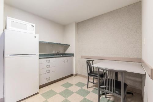 汉密尔顿汉密尔顿会议中心公寓酒店 的厨房配有白色冰箱、桌子和椅子