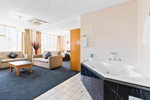 阿德莱德阿德莱德国际汽车旅馆的带浴缸的大浴室和客厅。