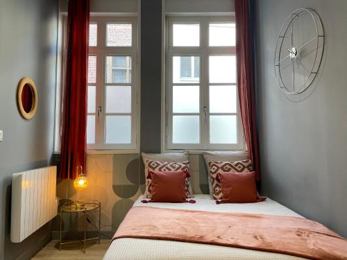 瓦朗西纳Studio Vieux Valenciennes的一间卧室设有2扇窗户和1张带枕头的床