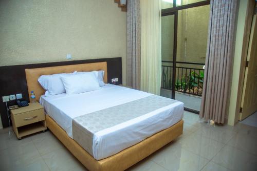基加利QUALITY INN HOTEL Kigali的一间卧室设有一张床和一个阳台