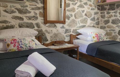 桑加拉达Marios guesthouse Pelion的一间卧室设有两张床和石墙