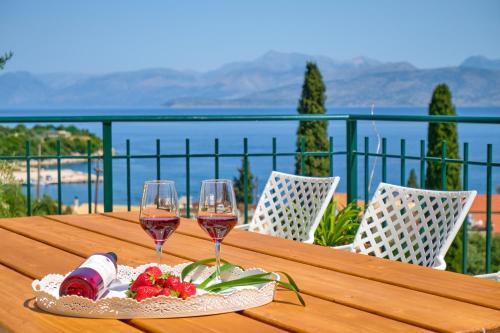 卡西奥皮Villa Spiros Imerolia Kassiopi的一张木桌,上面放有两杯葡萄酒和草莓