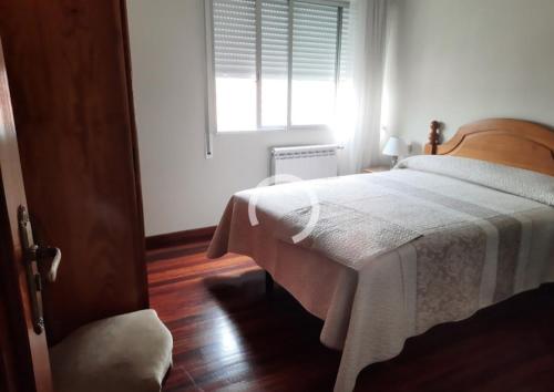 科巴罗Combarro vivienda completa próxima a sanxenxo的一间卧室配有一张带白色毯子的床和窗户。