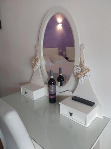 卡麦奥雷B&B Villa la Bouganville的镜子和桌子上的两瓶葡萄酒