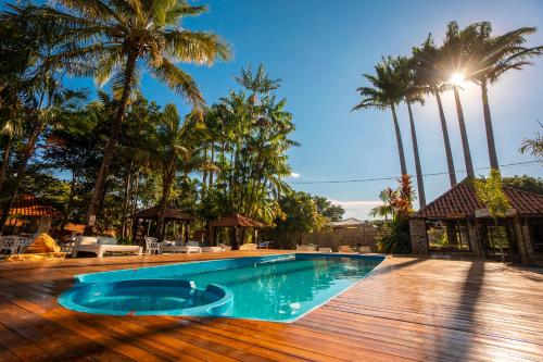 皮雷诺波利斯Pousada Villa das Pedras的一个带木甲板和棕榈树的游泳池