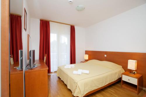 波尔Villa Daniela的一间卧室配有床、电视和红色窗帘