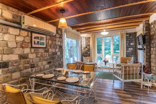 奈尼塔尔Sakley's Cottages的客厅设有石墙和桌椅