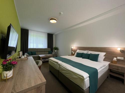 斯维德尼克Hotel Slávia Svidník SPA & RESTAURANT的酒店客房设有一张大床和一张沙发。
