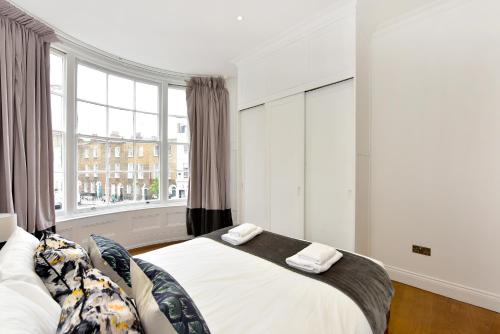 伦敦London Choice Apartments - Chelsea - Sloane Square的一间卧室设有一张床和一个大窗户