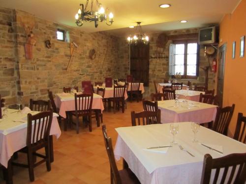 Santa Colomba de SomozaHotel Rural El Molinero de Santa Colomba de Somoza的一间设有白色桌椅的餐厅,拥有砖墙