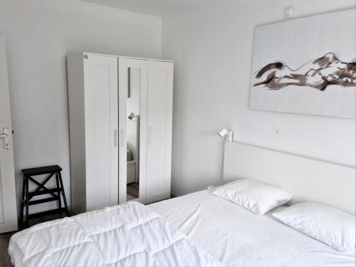 尼乌波特Appartement 2 chambres 200m plage Nieuwpoort Bad的白色卧室配有床和镜子