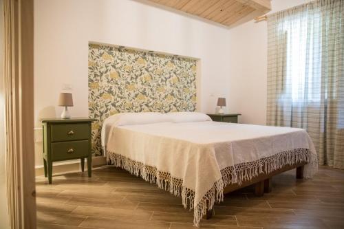 马拉泰亚Casale De Filippo的一间卧室设有床和两张桌子,还有一面墙
