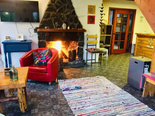 普孔Hostel Raíz的客厅设有红色椅子和壁炉