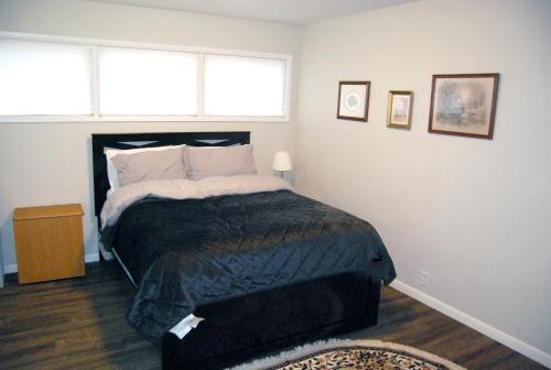 布卢明顿Hoosier Inn- Indiana University的一间卧室配有一张带黑色棉被的床和两个窗户。