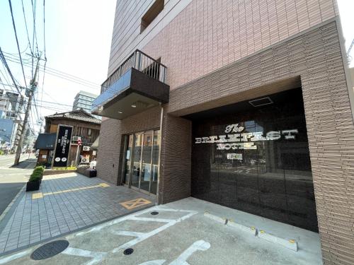 福冈The BREAKFAST HOTEL Fukuoka Tenjin的街道上建筑物前面的商店