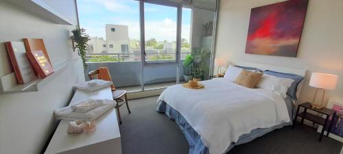 墨尔本beautiful apartment 100mts near the beach in Port Melbourne的一间卧室设有一张床和一个大窗户
