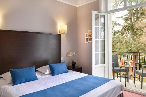 萨勒布里Logis Hôtel Restaurant Le Parc的一间卧室配有一张带蓝色枕头的床和一个阳台