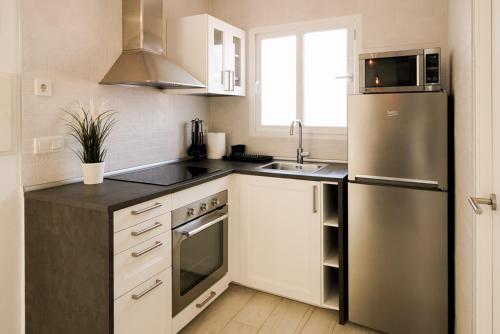 贝尼多姆Casa MYA con terreno privado y parking compartido - a 800m de Playa Poniente的厨房配有白色橱柜和不锈钢冰箱
