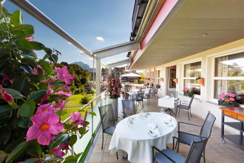 卢塞恩巴尔姆酒店的庭院配有白色的桌椅和粉红色的鲜花