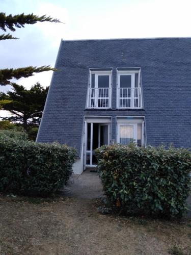 吉代勒Charmant logement vue mer avec chambre et terrasse的蓝色屋顶房屋,设有白色窗户和灌木