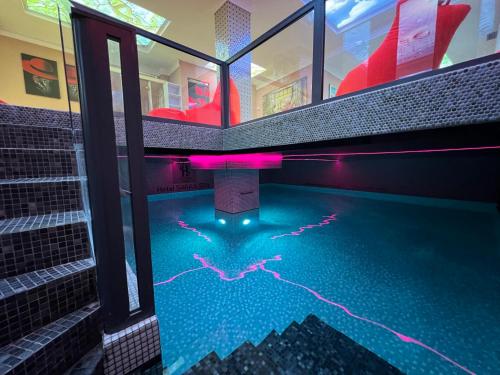 普里什蒂纳Hotel Sara & SPA的一座游泳池,在大楼里设有粉红色的灯光