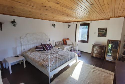 斯莫梁Guest house Smolyan的卧室设有白色的床和木制天花板。