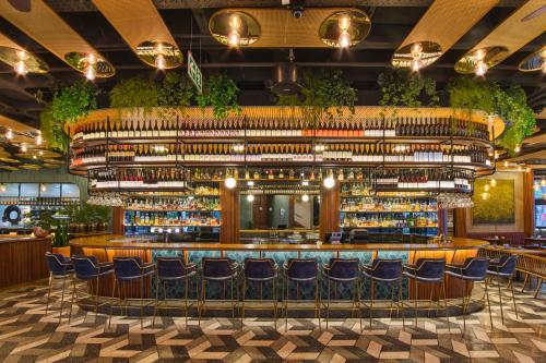 约翰内斯堡voco Johannesburg Rosebank an IHG Hotel的餐厅内带蓝色椅子的酒吧