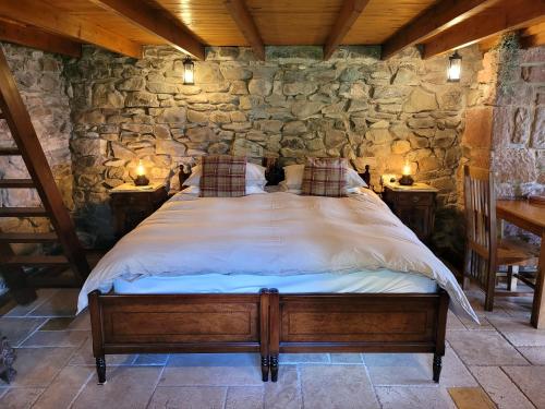 巴尔马哈Loch Lomond shore Boat House的卧室配有一张石墙内的大床