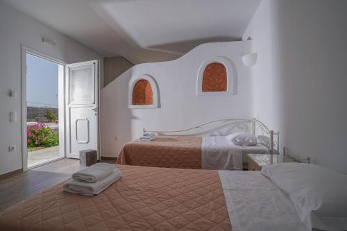 格拉斯托斯Casa Nostra Mykonos Boutique Rooms & Studios的一间卧室设有两张床和大窗户