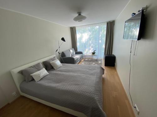 派尔努Lovely Aisa studio in Pärnu的一间卧室配有一张床、电视和椅子