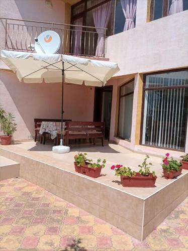 阳光海滩Villa Mars的天井配有桌子、雨伞和盆栽植物