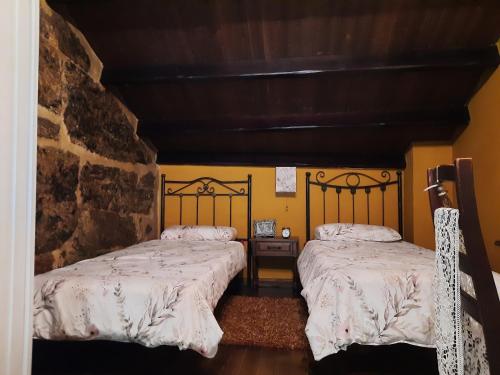 OrosoCasa Rural Cabo de Aráns的黄色墙壁客房的两张床