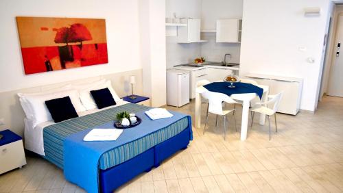 莱乌卡La Corte di Leuca Residence & SPA的一间卧室配有一张床铺和一张桌子,还设有一间厨房