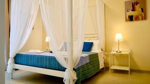 莱乌卡La Corte di Leuca Residence & SPA的一间卧室配有带窗帘的天蓬床