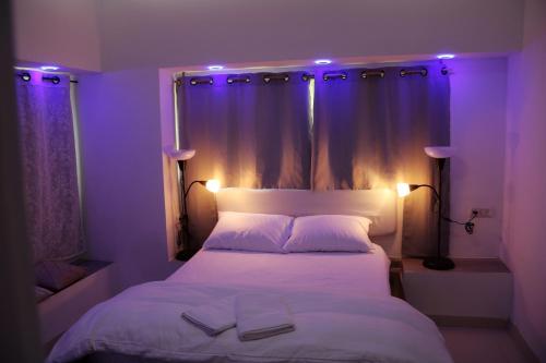 阿拉德במיוחד בשבילך צימר ערד的一间卧室配有白色床和紫色照明