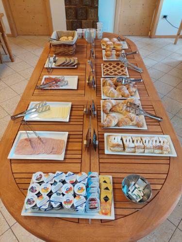 Pieve Tesino塔克斯旅舍的一张长木桌,上面放着不同类型的糕点