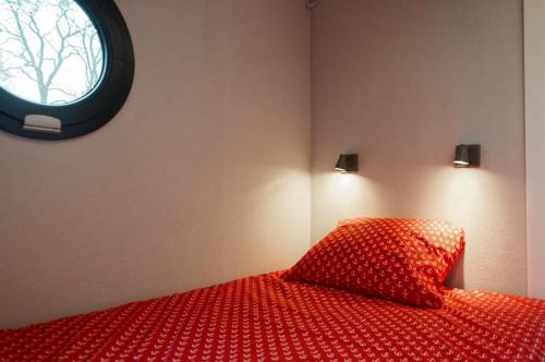 奥瓦瓦Apartament na wodzie - Riveraparts - Marina Oława的一间卧室配有一张红色的床和圆形窗户