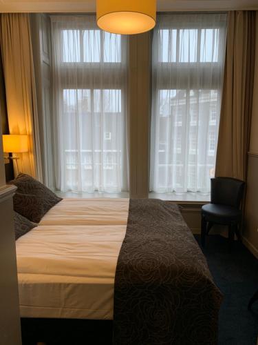 阿姆斯特丹克莱门斯酒店的一间卧室配有一张床、一把椅子和窗户。