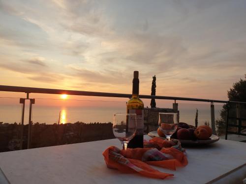阿约斯尼奇塔斯Lavender House 1 - Agios Nikitas的一张桌子上的一瓶葡萄酒和玻璃杯,享有日落美景
