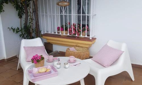 埃尔博斯克Mi casita del Bosque的一张带两把椅子的白色桌子和一扇鲜花窗口