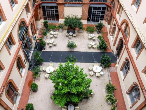 图卢兹宜必思风格图卢兹卡皮托勒酒店的享有庭院的顶部景色,庭院内种植了桌子和植物