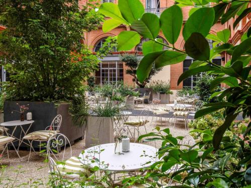 图卢兹宜必思风格图卢兹卡皮托勒酒店的一个带桌椅的庭院和一座建筑