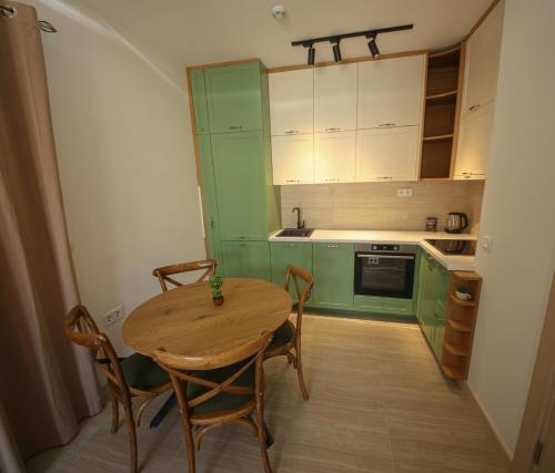 巴尔Luxury Mare apartment的厨房配有绿色橱柜和木桌及椅子