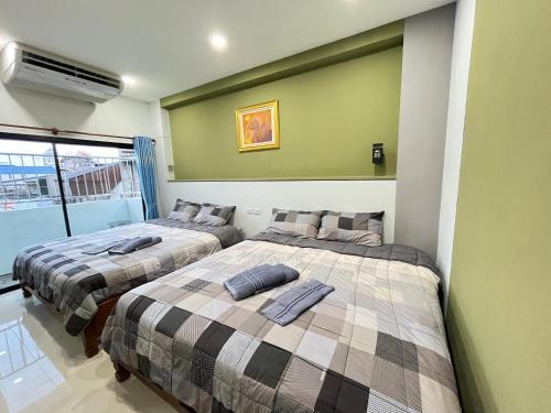 合艾Variety winner hostel的绿墙客房内的两张床