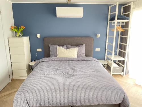 HamTiny House in Limburg bij Kelly & Nick的一间卧室配有一张蓝色墙壁的床