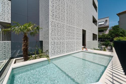 斯普利特Luxury Apartments Villa Mala Split的棕榈树建筑前的游泳池