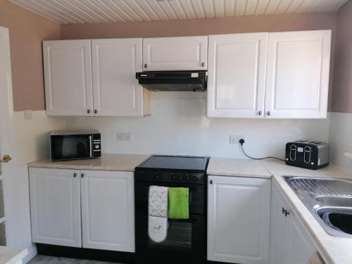 PrestonpansBeautiful three bedroom seaside retreat的厨房配有白色橱柜和黑色用具